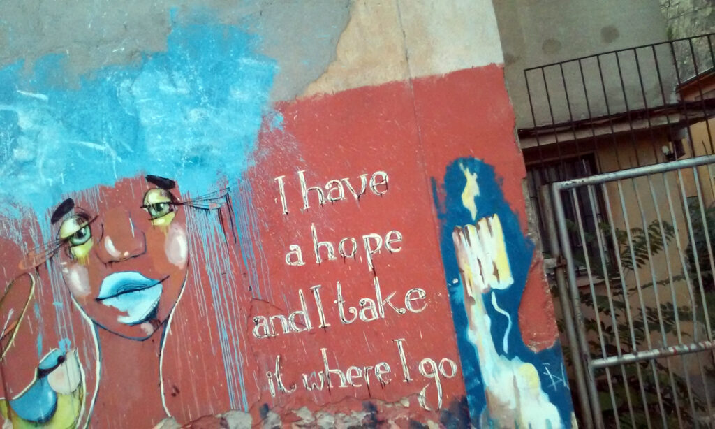 Unikalny mural – przedstawia kobiecą twarz z niebieskimi włosami oraz napis „I have a hope and I take it where I go”.